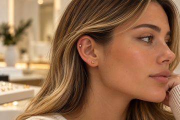 Close-up of an ear wearing titanium and 14K gold piercing jewelry, showcasing different metal options and minimalist piercing styles.