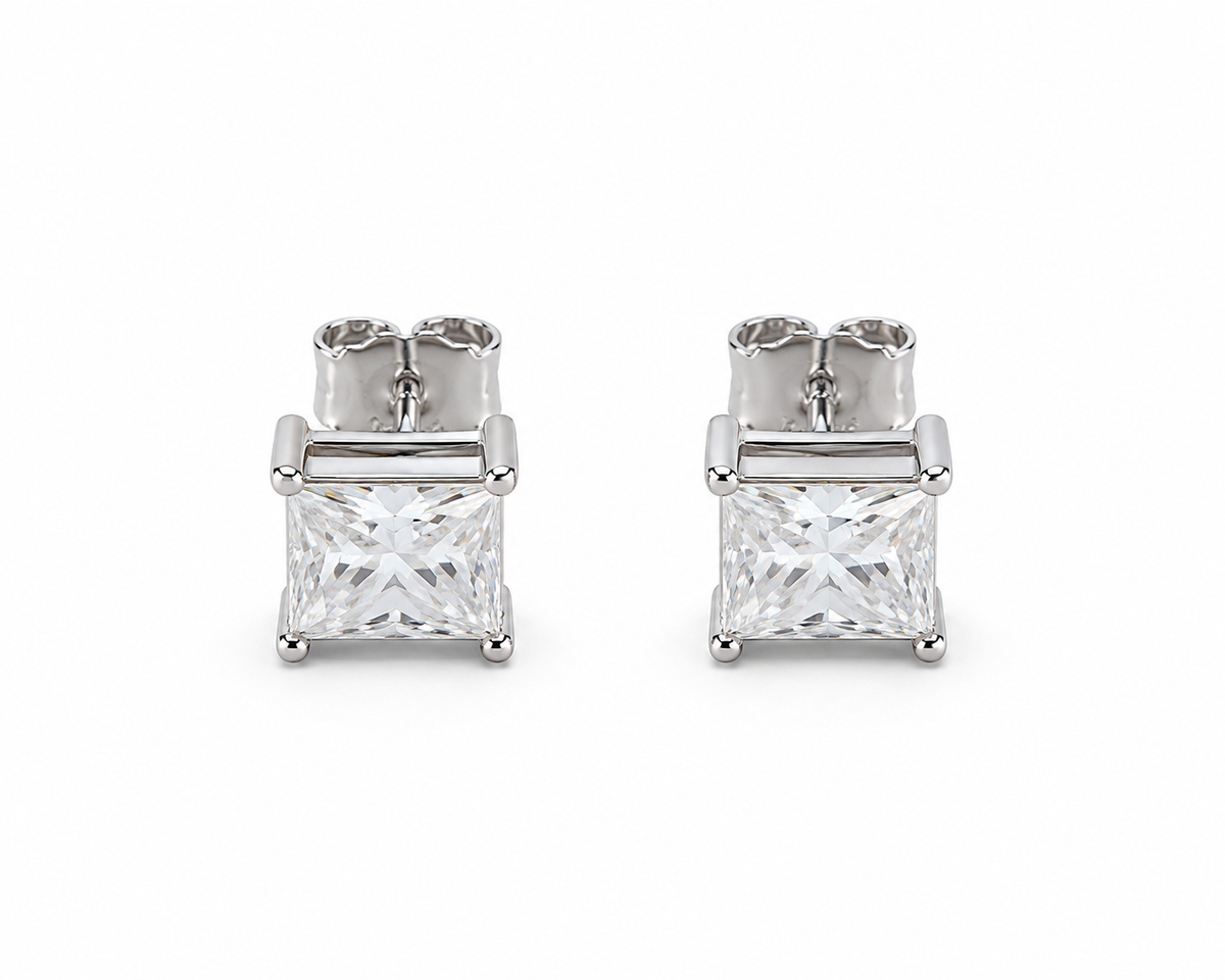 A pair of princess-cut diamond stud earrings in a silver-toned four-prong setting, shown from the back on a clean white background.